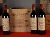 three bottles of red wine sitting next to a wooden box