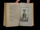 someone is holding an open book with a drawing of a woman in a dress