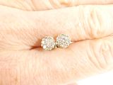 an image of a woman ' s hand holding a pair of diamond stud earrings