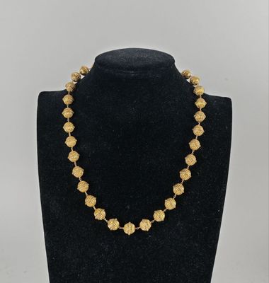 a gold necklace on a mannequin display with a black mannequin