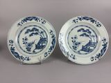 pair of blue and white plates with a landscape scene on them