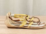 yellow and white sandals with braid straps on a wooden surface