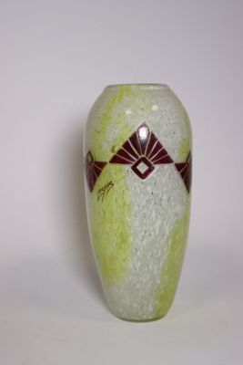 un vase vert orné d'un motif sur un fond blanc