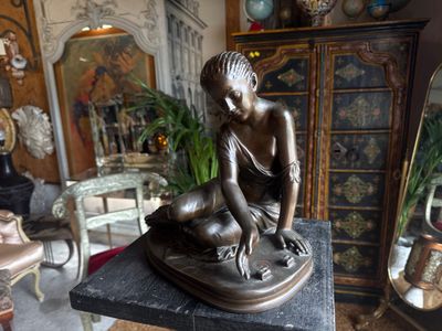 a bronze statue of a woman sitting on a table