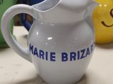 a white pitcher with blue writing on it sitting on a table