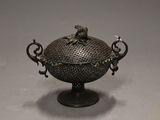 an old metal bowl with a bird on it sitting on top of a table