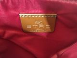 a close up of a red purse with a gold metal tag