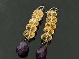 une paire de boucles d'oreilles en améthorate et citrine posées sur un fond noir