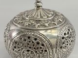 an ornate silver box with a lid on a white background