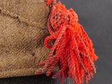 a close up of a hat with a red tassel on top of it