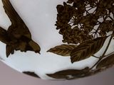 a white vase with a bird and flowers on it