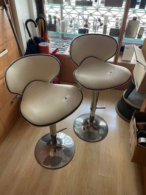 two white leather bar stools sitting on top of a hard wood floor