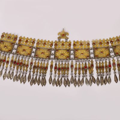 a close up of a gold and red necklace on a white surface