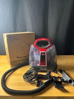 un aspirateur rouge et noir posé sur une table en bois, à côté d'une boîte