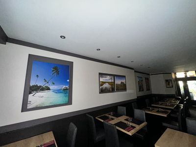 tables and chairs in a restaurant with pictures on the wall