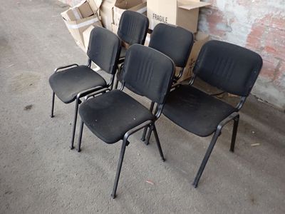 quatre chaises noires placées devant un mur de briques