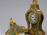 une horloge verte et dorée posée à côté d'un parapluie vert et doré