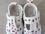pair of white shoes with red hearts on them sitting on a couch