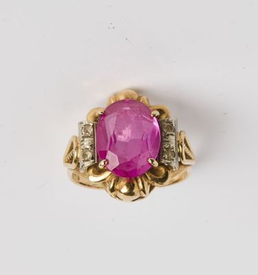 un gros plan d'une bague en pierre rose et diamants posée sur une surface blanche