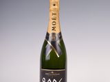une bouteille de champagne posée sur une table blanche, sur fond gris