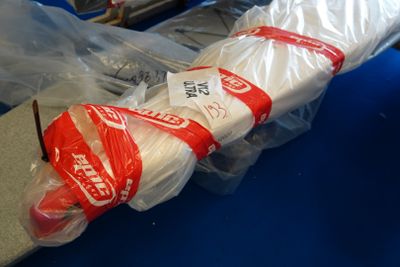 un grand parapluie blanc emballé dans du plastique, posé sur une table