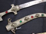 two swords that are sitting on a black surface