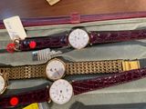 three watches are in a case on a table next to a pair of scissors