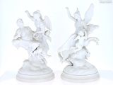 pair of white porcelain figurines of angels on a pedestal