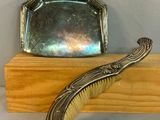 un porte-monnaie en argent et une brosse posés sur une étagère en bois