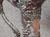 une cruche en argent ornée de raisins, posée sur une table