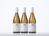 three bottles of white wine sitting on top of a table