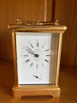 une horloge en or posée sur une table en bois devant un mur
