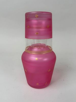 vase en verre rose orné d'étoiles dorées sur un fond blanc