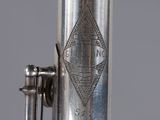 a close up view of a silver flute with a diamond on it