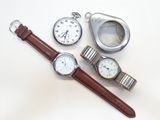 trois montres et une montre de poche posées sur une surface blanche
