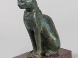 statue of a cat sitting on a base on a white background