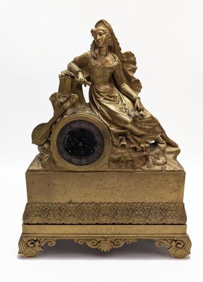 une horloge en or avec une femme assise dessus