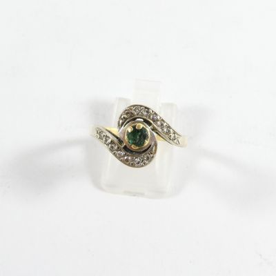 gros plan d'une bague avec une pierre verte entourée de diamants