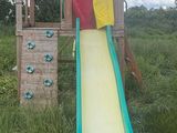 a wooden slide in the middle of a grassy field