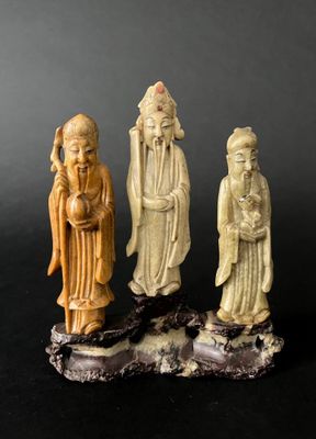 three chinese carved figurines of men and women on a black surface
