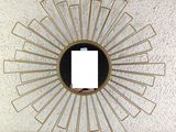a gold sunburst mirror hanging on a white wall