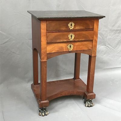 une petite table en bois à deux tiroirs, montée sur roulettes