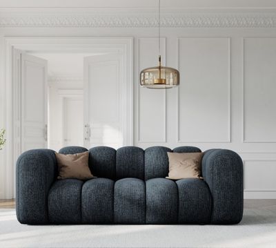 un grand canapé bleu placé dans un salon, près d'un mur blanc