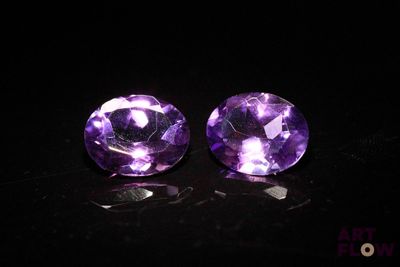 a pair of purple amethtites sitting on top of a black surface