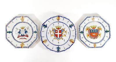 three plates with a coat of arms on them on a white surface