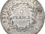 a silver coin with a wreath on the front of it