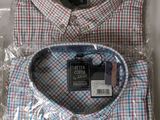 two men ' s shirts wrapped in plastic on top of a table
