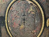 a black and gold painted cabinet with a clock on it