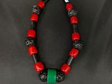 a red and black necklace with a green bead