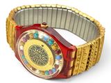 une montre rouge et dorée sur un fond blanc
